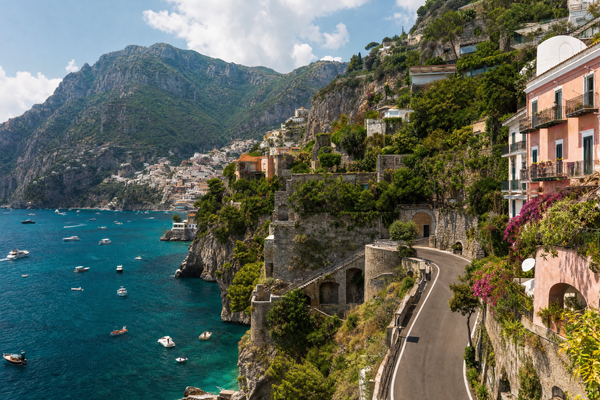 Colorful cliffside villages of the Amalfi Coast seen from the sea, with boats and bright sunlight