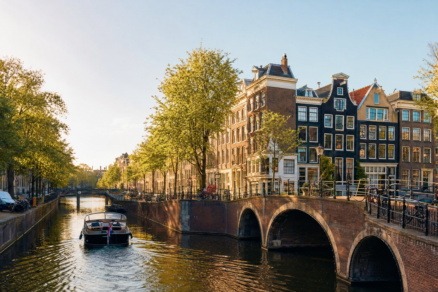 Canal in Amsterdam with boats and bicycles at sunset