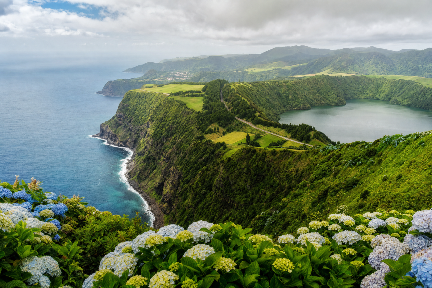 Dramatic volcanic lakes and lush greenery in the Azores with hikers enjoying the view.