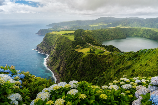 Dramatic volcanic lakes and lush greenery in the Azores with hikers enjoying the view.