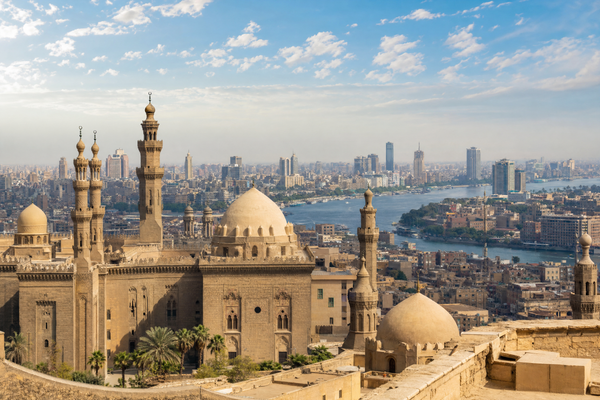 The sun rises over Cairo, illuminating the Pyramids and cityscape.