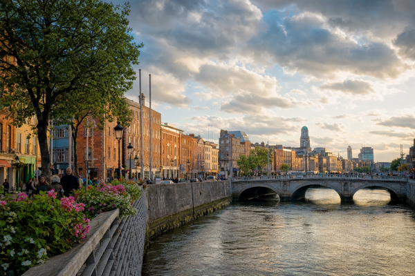 Dublin cityscape with changing seasonal colors along the River Liffey, under a partly cloudy sky