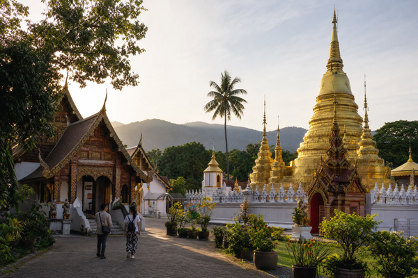 Affordable street scene in Chiang Mai with temples, food stalls, and tuk tuks.