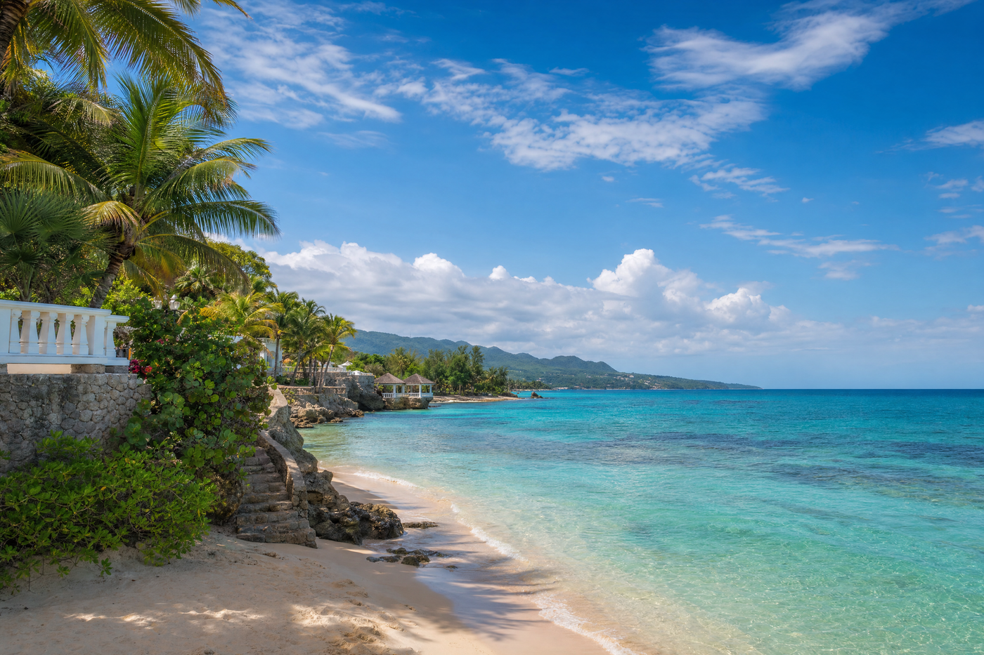 Tourists relaxing on a free beach in Jamaica with lush scenery in the background