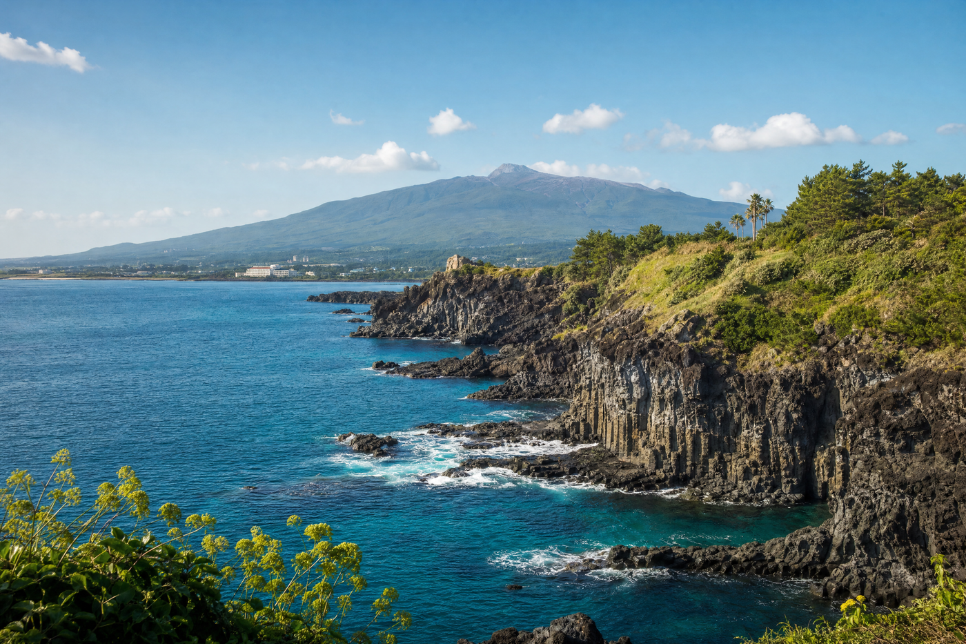 Emerald coastline and volcanic cliffs of Jeju Island under a clear sky