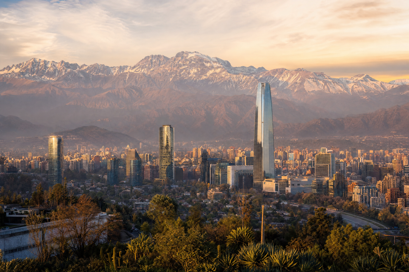 A panoramic view of Santiago, Chile, with the Andes mountains in the background on a sunny day.