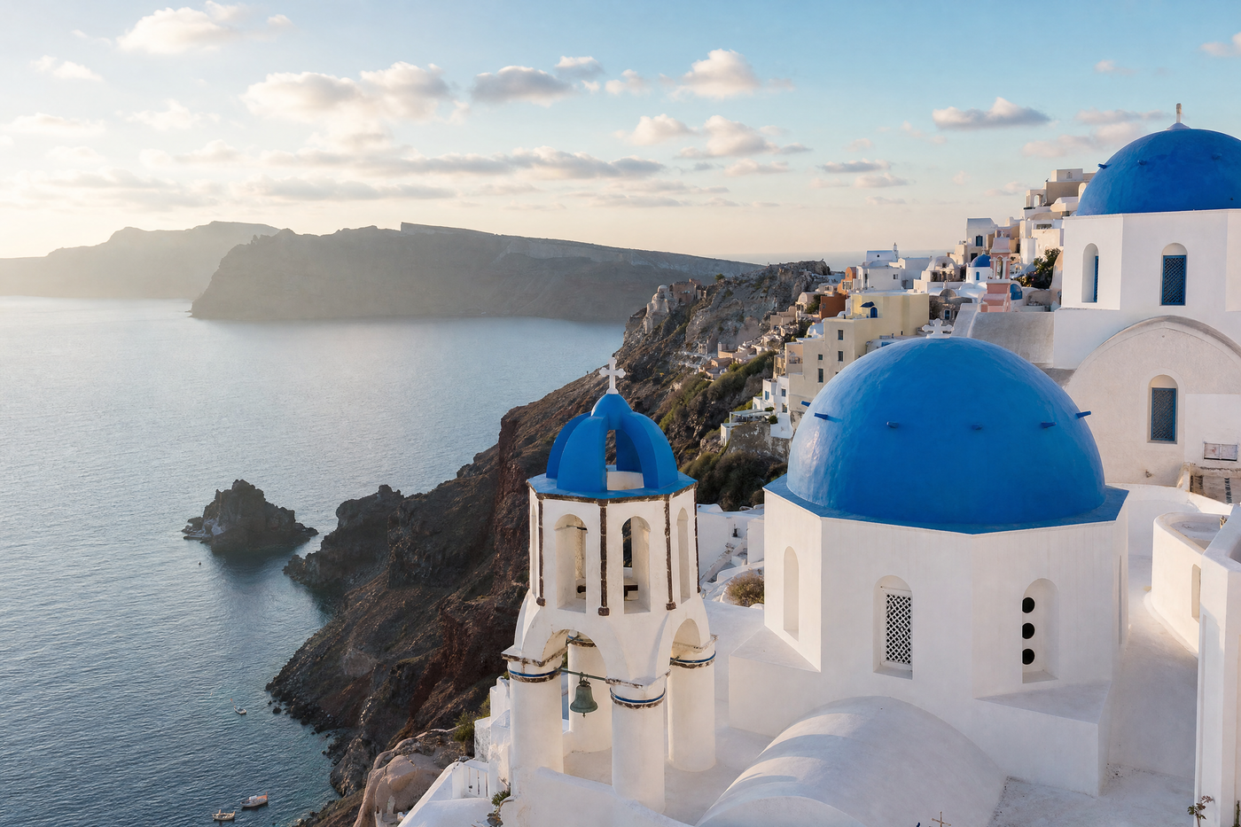Oia's blue-domed churches and white houses overlooking the Aegean Sea in Santorini, Greece