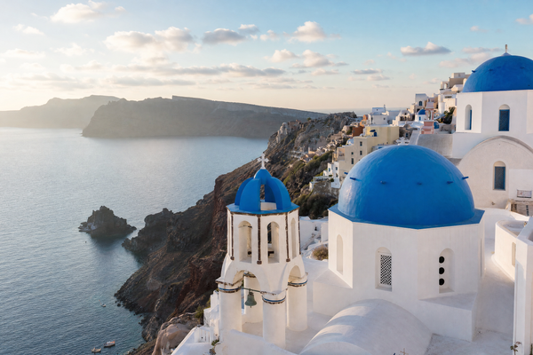 Oia's blue-domed churches and white houses overlooking the Aegean Sea in Santorini, Greece