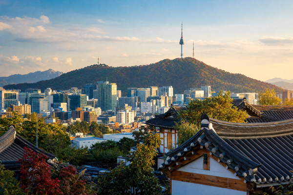 Traditional hanok rooftops with the modern Seoul skyline in the background