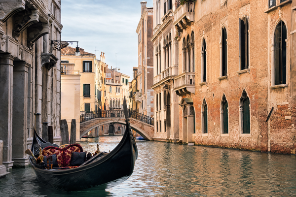 Venetian canal with gondolas and colorful buildings under a soft morning light.